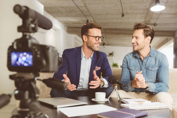 Two men sitting on sofa and recording a video