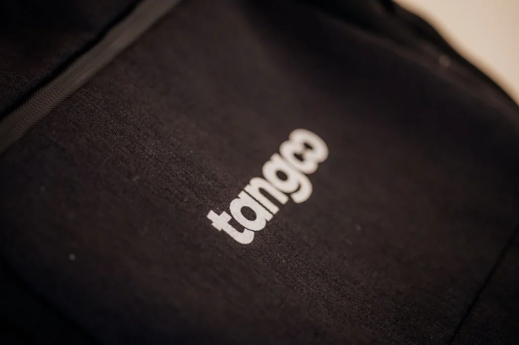 Close-up of a black fabric with the white "tango" logo.
