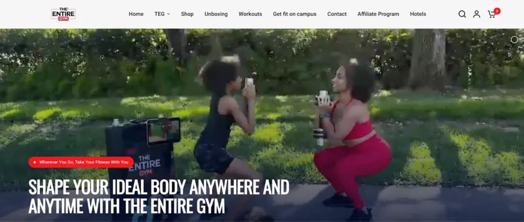 Two women perform squats outdoors, one in a black outfit and one in red, with a portable gym setup beside them.