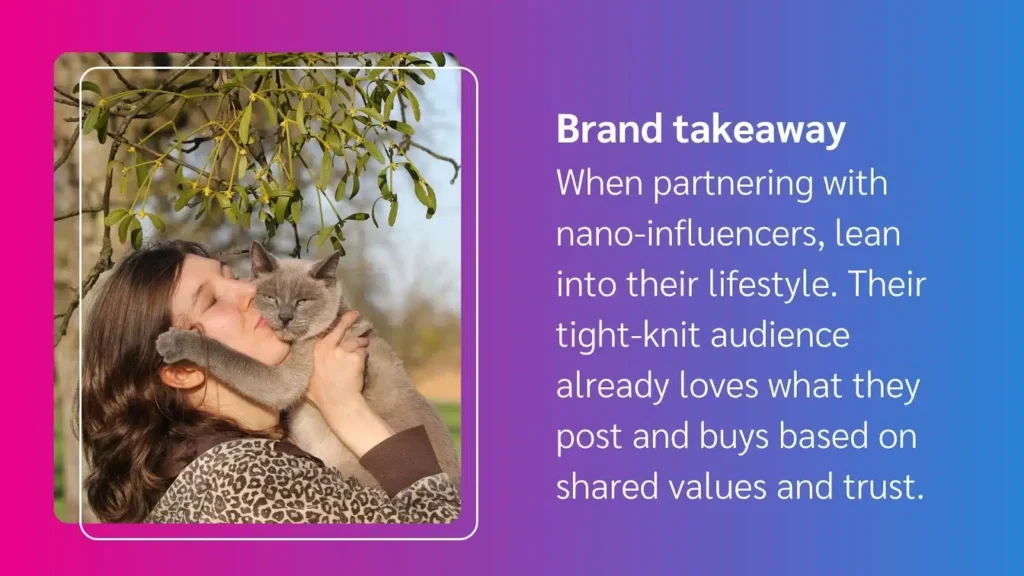 A woman wearing a leopard-print top holds a grey cat close, surrounded by green leaves and a blurred outdoor background.