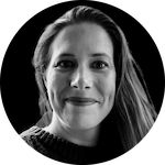 A woman with long, wavy hair is partially visible against a dark background, wearing a textured sweater.