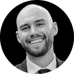 A bald man in a formal suit and tie, posed against a dark background, conveying a professional demeanor.