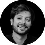 A close-up portrait of a person with tousled hair, set against a solid black background.