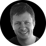 A monochrome circular portrait featuring a person with short, styled hair against a dark background.